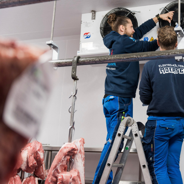 Chef und Mitarbeiter bei der Wartung einer Anlage in einer Fleischerei