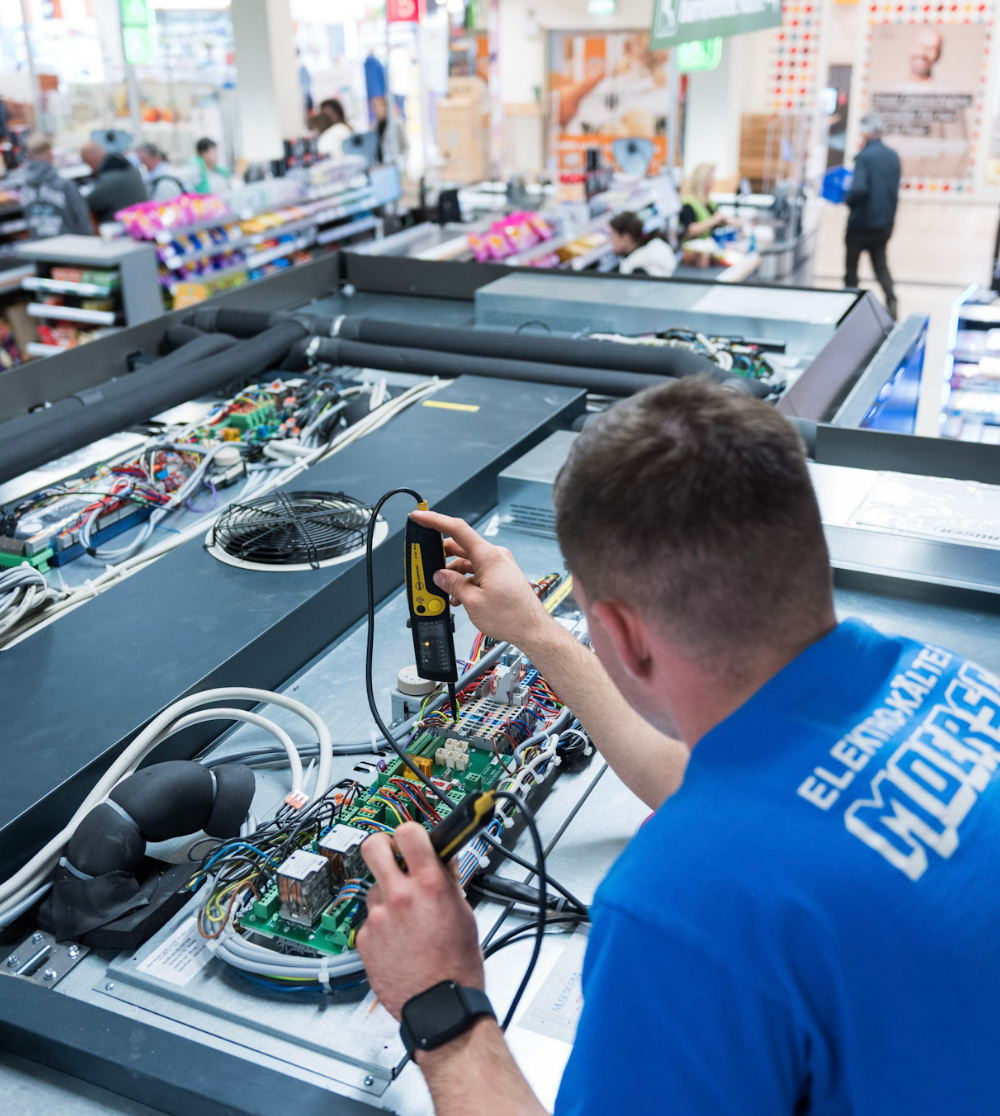 Mitarbeiter bei Wartung auf einem Kältemöbelstück im Supermarkt